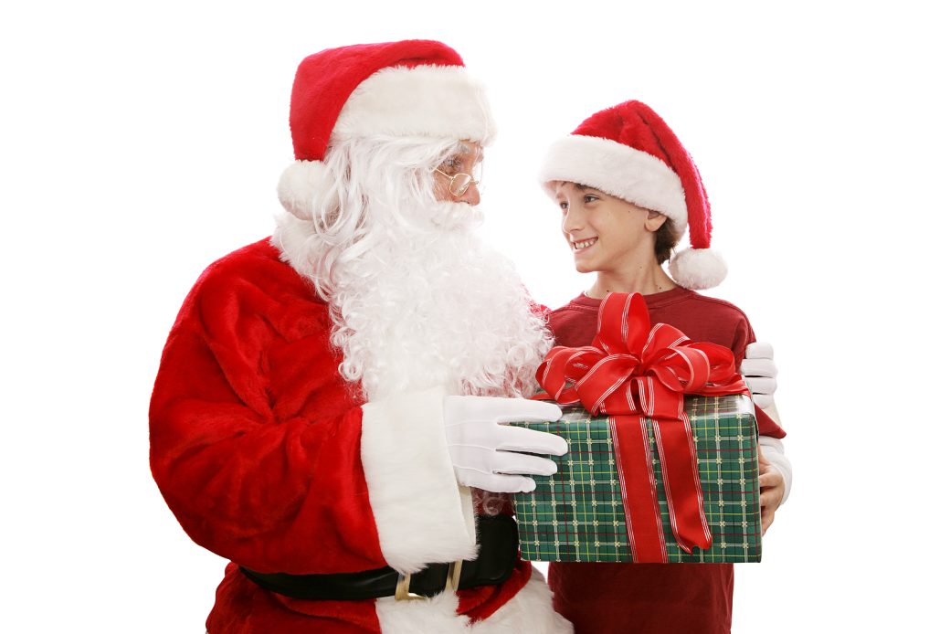 A cute little boy receiving a big present from Santa. Isolated on white.