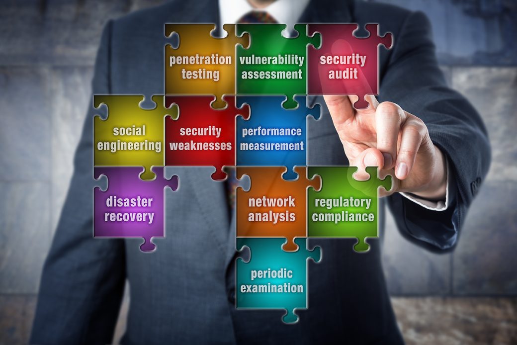 IT manager is doing a virtual puzzle made of pieces labeled with security audit terminology. Information systems concept for computer security audit vulnerability assessment and penetration testing.