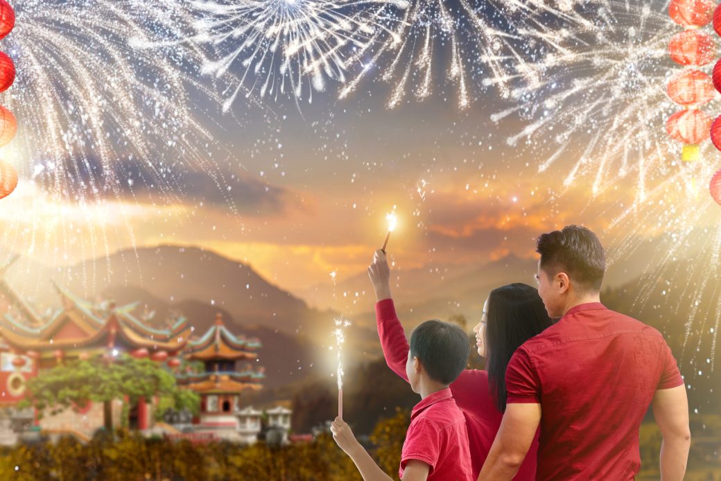 Chinese New Year lanterns and firework. Family celebrating Lunar new year. Asian parents and child with firecrackers. Celebration in Asia. Mother, father and child watch fireworks and red lanterns.